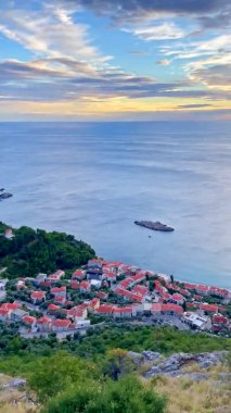 Dikey video. Karadağ 'ın Budva kenti yakınlarındaki Sveti Stefan adası yakınlarındaki körfez perspektifinden panoramik çekim.