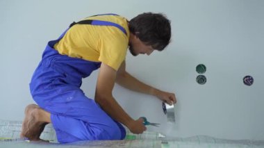 Profesyonel bir yer altı ısıtma tesisatı ustası zemine yalıtım malzemelerini yapıştırıyor.