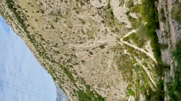 Vídeo vertical. Disparo en cámara lenta. El niño está sentado en una roca en un camino al castillo sobre el casco antiguo de Kotor. Viajes a Montenegro concepto — Vídeo de stock