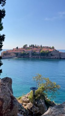 Dikey video. Genç kadın Sveti Stefan adası yakınlarındaki parkı ziyaret ediyor. Budva şehrinin yakınlarında ünlü bir turistik mekan. Karadağ 'a Seyahat