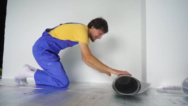 Επαγγελματίας μάστορας στην εγκατάσταση ενδοδαπέδια θέρμανσης κατασκευάζει την υπέρυθρη θερμαντική μεμβράνη — Αρχείο Βίντεο