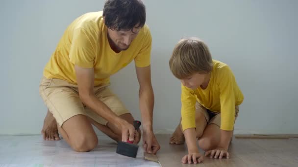 Pai e seu filho instalam laminado no chão em seu apartamento. Conceito DIY — Vídeo de Stock