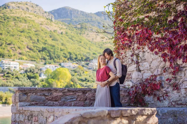 Homem e mulher turistas no fundo da bela vista da ilha de Santo Estêvão, Sveti Stefan no Budva Riviera, Budva, Montenegro. Viajar para Montenegro conceito — Fotografia de Stock