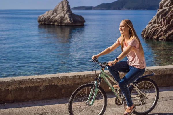 Woman tourist on a bicycle explores Budva in Montenegro. Cycling in Montenegro concept — Stock Photo, Image