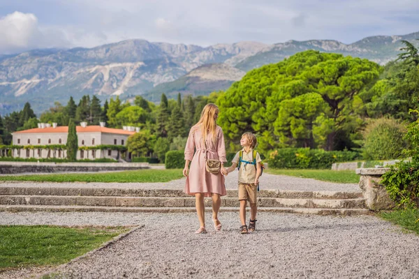 Mãe e filho turistas andando juntos em Montenegro. Paisagem panorâmica de verão do belo parque real verde Milocer na margem do Mar Adriático, Montenegro — Fotografia de Stock