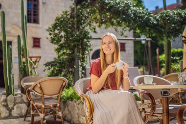 Genç bayan turist, eski Budva kasabasında kahve içiyor. Karadağ 'a Seyahat