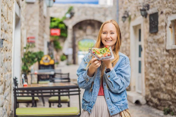 Ung kvinna turist äter traditionell pizza i gamla stan i Budva. Resor till Montenegro konceptet — Stockfoto