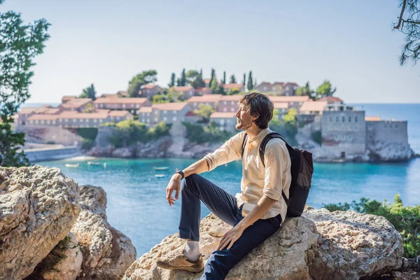 Homem turista no fundo da bela vista da ilha de Santo Estêvão, Sveti Stefan no Budva Riviera, Budva, Montenegro. Viajar para Montenegro conceito — Fotografia de Stock