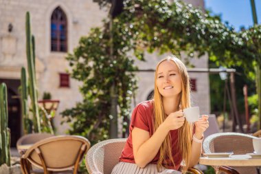 Genç bayan turist, eski Budva kasabasında kahve içiyor. Karadağ 'a Seyahat