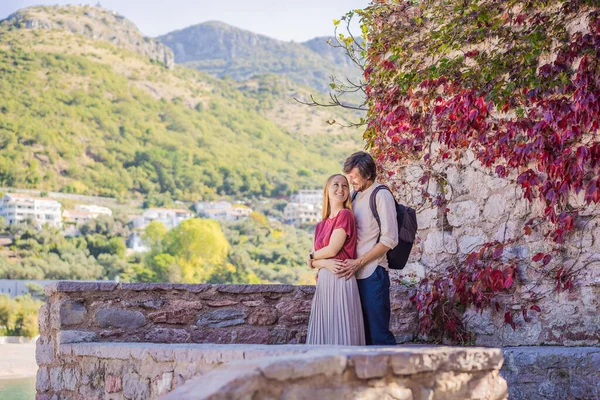 Homem e mulher turistas no fundo da bela vista da ilha de Santo Estêvão, Sveti Stefan no Budva Riviera, Budva, Montenegro. Viajar para Montenegro conceito — Fotografia de Stock