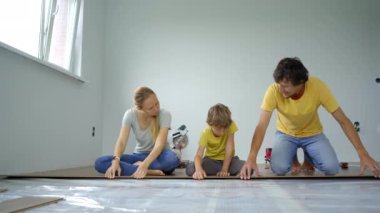 Anne, baba ve oğuldan oluşan bir aile dairelerinin zeminine kaplama döşedi. DIY kavramı