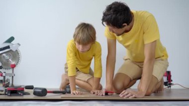 Baba ve küçük oğlu dairelerinde yere kaplama döşemişler. DIY kavramı