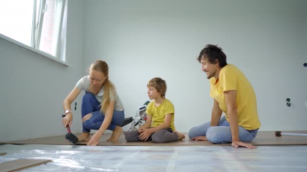 Uma família de mãe, pai e filho instalar laminado no chão em seu apartamento. Conceito DIY — Vídeo de Stock