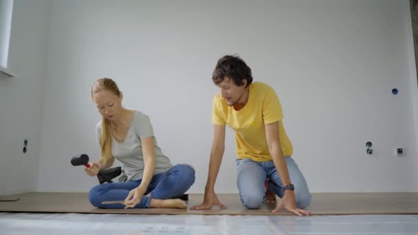 Sebuah keluarga wanita dan pria memasang laminasi di lantai apartemen mereka. Konsep DIY — Stok Video