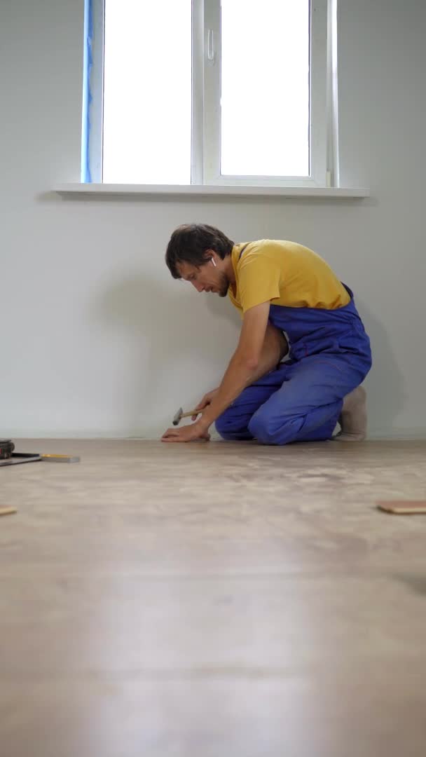 Verticale video. Een man professionele laminaat installateur leggen laminaat hout — Stockvideo