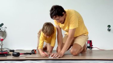 Baba ve küçük oğlu dairelerinde yere kaplama döşemişler. Diy konsepti. Yavaş çekim videosu