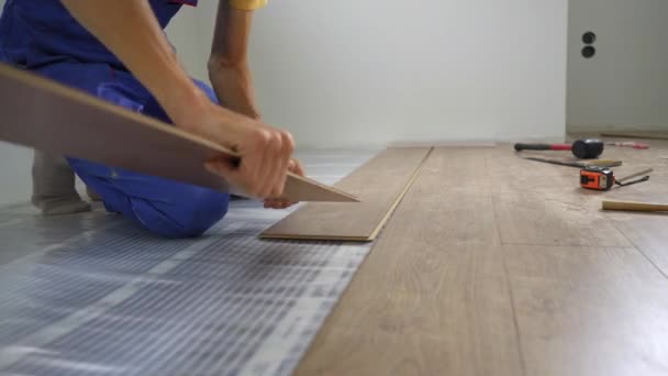 Een man professionele laminaat installateur leggen laminaat hout — Stockvideo