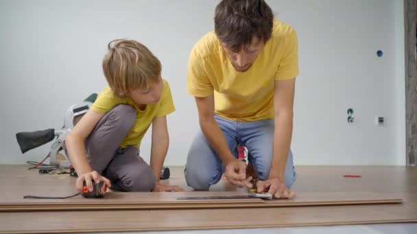 Vater und kleiner Sohn verlegen Laminat auf dem Fußboden in ihrer Wohnung. DIY-Konzept — Stockvideo