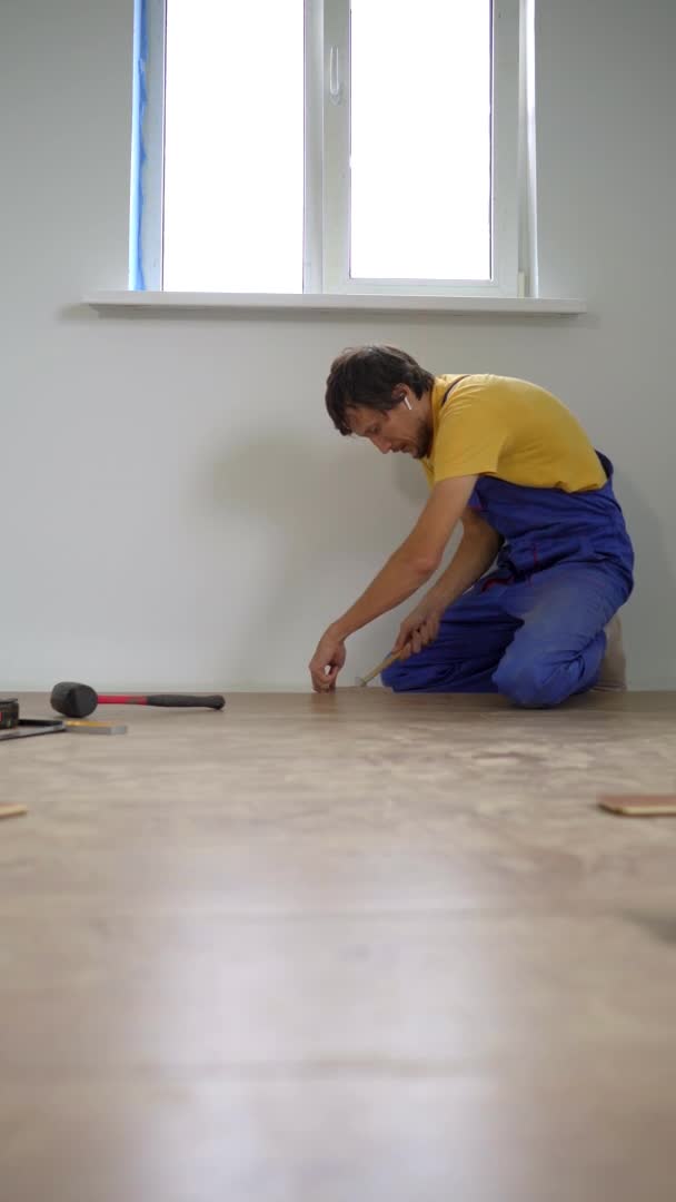 Vídeo vertical. Um homem profissional instalador laminado que estabelece madeira laminada — Vídeo de Stock