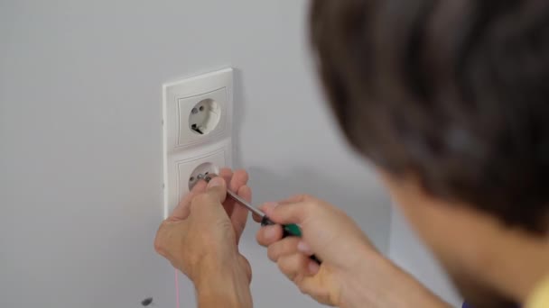 En elektriker monterar ett eluttag i väggen. Byggande och reparation av bostäder — Stockvideo