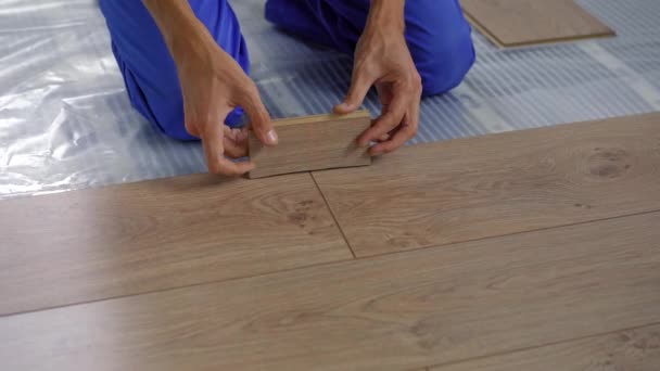 Een man professionele laminaat installateur leggen laminaat hout — Stockvideo