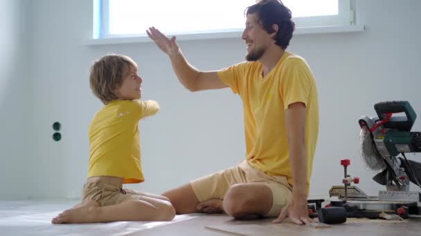 父亲和他的小儿子在他们公寓的地板上安装了层压板。DIY概念 — 图库视频影像