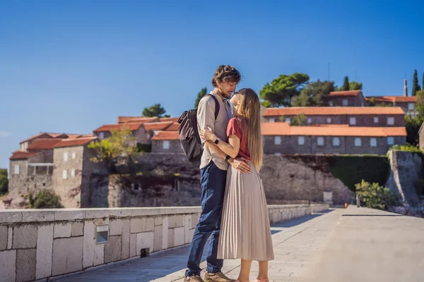 Homem e mulher turistas no fundo da bela vista da ilha de Santo Estêvão, Sveti Stefan no Budva Riviera, Budva, Montenegro. Viajar para Montenegro conceito — Fotografia de Stock