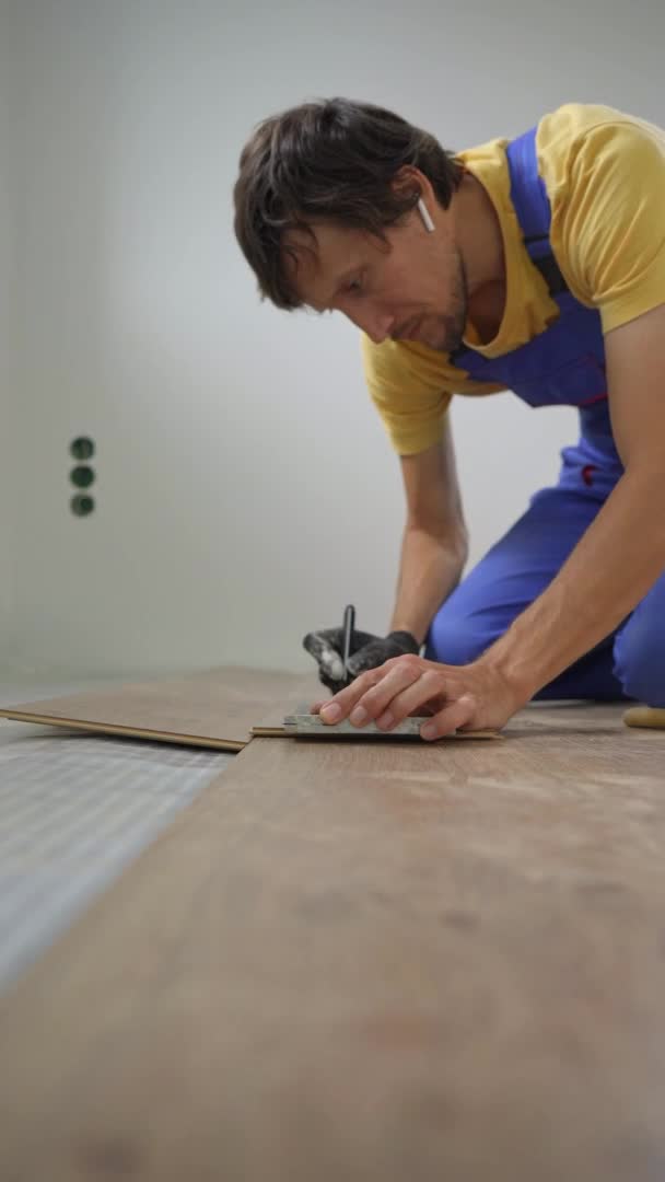 垂直录像。一名男子专业的层压板安装工铺设层压板木料 — 图库视频影像