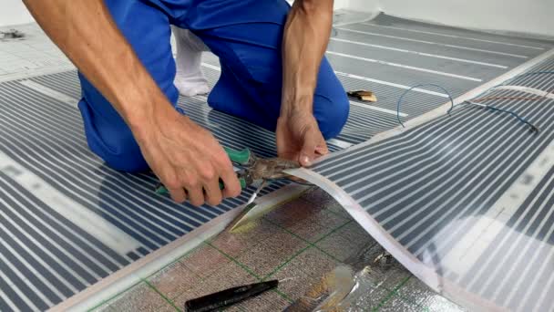 Slowmotion video. A professional master of underfloor heating installation connects the infrared heating film to the electric circuit. Closeup shot — Stock Video