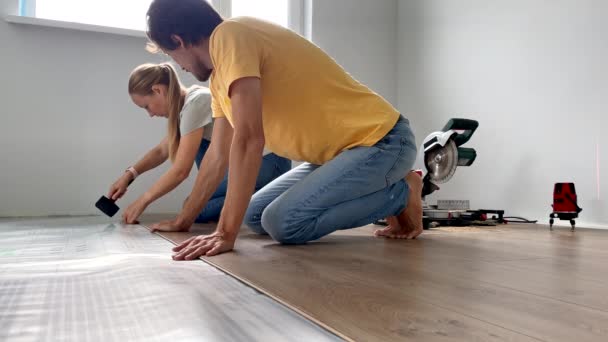 一个男女家庭在他们公寓的地板上安装了层压板。DIY概念。慢动作视频 — 图库视频影像