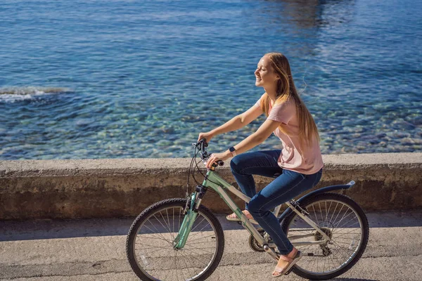 Vrouw toerist op een fiets verkent Budva in Montenegro. Fietsen in Montenegro concept — Stockfoto