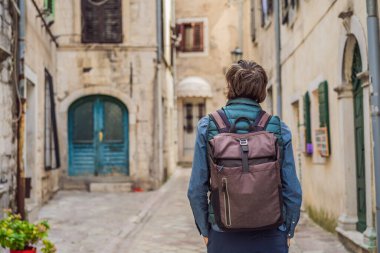 Karadağ 'ın eski Kotor kasabasında güneşli bir günde renkli caddenin tadını çıkaran erkek turist. Karadağ 'a Seyahat