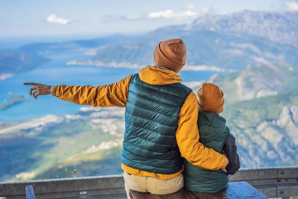 Baba ve oğul gezginler Kotor 'un manzarasından hoşlanırlar. Karadağ. Kotor Körfezi, Kotor Körfezi, Boka Kotorska ve eski şehrin duvarları. Çocuklarla Karadağ 'a seyahat etmek. Kotor 'un tahkimatları devrede — Stok fotoğraf