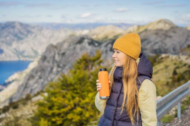 Kadın turist Kotor 'un manzarasından hoşlanıyor. Karadağ. Kotor Körfezi, Kotor Körfezi, Boka Kotorska ve eski şehrin duvarları. Karadağ 'a seyahat. Kotor 'un tahkimatları UNESCO Dünya Mirası' nda