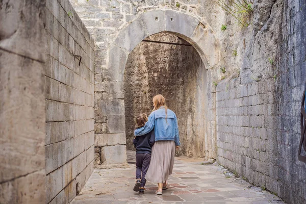 Mom and son travelers enjoying Colorful street in Old town of Kotor on a sunny day, Montenegro. Travel to Montenegro concept — стоковое фото