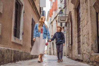 Anne ve oğul gezginler, Karadağ 'ın eski Kotor kasabasında güneşli bir günde renkli caddelerin tadını çıkarıyorlar. Karadağ 'a Seyahat