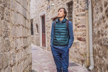 Karadağ 'ın eski Kotor kasabasında güneşli bir günde renkli caddenin tadını çıkaran erkek turist. Karadağ 'a Seyahat