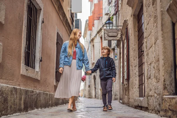 Mom and son travelers enjoying Colorful street in Old town of Kotor on a sunny day, Montenegro. Travel to Montenegro concept — Stock Photo, Image