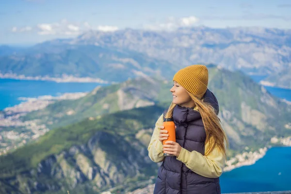 Kadın turist Kotor 'un manzarasından hoşlanıyor. Karadağ. Kotor Körfezi, Kotor Körfezi, Boka Kotorska ve eski şehrin duvarları. Karadağ 'a seyahat. Kotor 'un tahkimatları UNESCO Dünya Mirası' nda