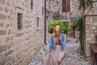 Karadağ 'ın eski Kotor kasabasında güneşli bir günde Renkli Sokak' ın tadını çıkaran kadın turist. Karadağ 'a Seyahat