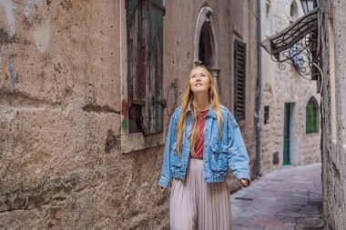 Karadağ 'ın eski Kotor kasabasında güneşli bir günde Renkli Sokak' ın tadını çıkaran kadın turist. Karadağ 'a Seyahat