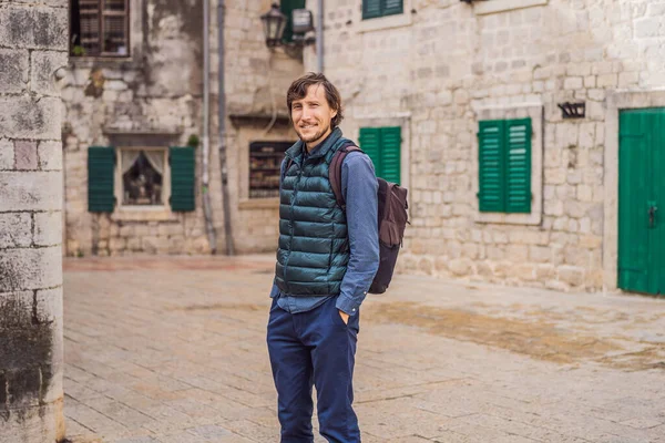 Karadağ 'ın eski Kotor kasabasında güneşli bir günde renkli caddenin tadını çıkaran erkek turist. Karadağ 'a Seyahat