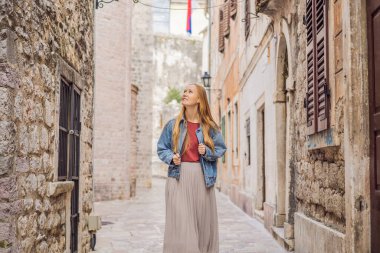 Karadağ 'ın eski Kotor kasabasında güneşli bir günde Renkli Sokak' ın tadını çıkaran kadın turist. Karadağ 'a Seyahat