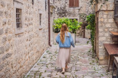 Karadağ 'ın eski Kotor kasabasında güneşli bir günde Renkli Sokak' ın tadını çıkaran kadın turist. Karadağ 'a Seyahat