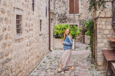 Karadağ 'ın eski Kotor kasabasında güneşli bir günde Renkli Sokak' ın tadını çıkaran kadın turist. Karadağ 'a Seyahat