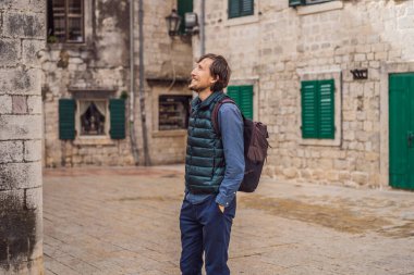 Karadağ 'ın eski Kotor kasabasında güneşli bir günde renkli caddenin tadını çıkaran erkek turist. Karadağ 'a Seyahat