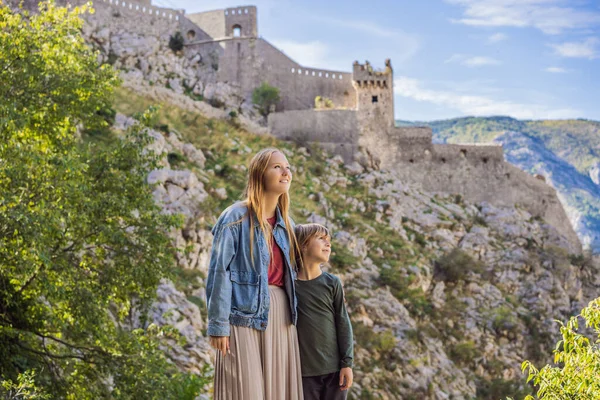 Mor och son resenärer har utsikt över Kotor. Montenegro. Kotorbukten, Kotorbukten, Boka Kotorska och muromgärdad gammal stad. Resa med barn till Montenegro koncept. Kotors befästningar är på gång — Stockfoto