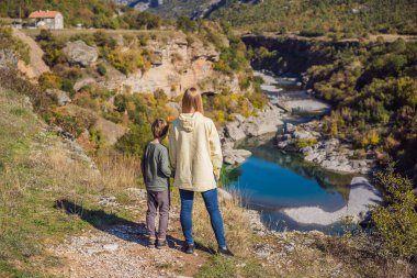 Karadağ. Anne ve oğul turistler, Moraca nehrinin temiz turkuaz suyunun arka planında yeşil moraca kanyonu doğa manzarasında. Karadağ 'da seyahat kavramı
