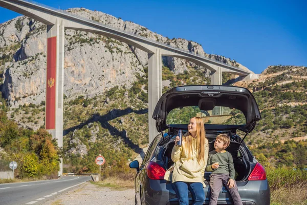 Montenegro. Mamma e figlio turisti sono seduti sul bagagliaio di una macchina. Viaggio in giro per Montenegro. Ponte Moracica. Ponte di cemento armato attraverso la gola di Moraci. Il Bar dell'autostrada - Bolyare. Il — Foto Stock
