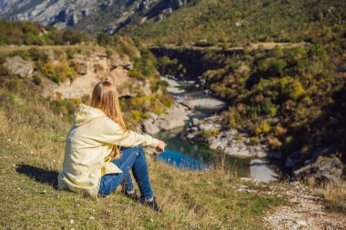 Karadağ. Moraca nehrinin temiz turkuaz suyunun arka planındaki kadın turist yeşil moraca kanyonu tabiatında. Karadağ 'da seyahat kavramı